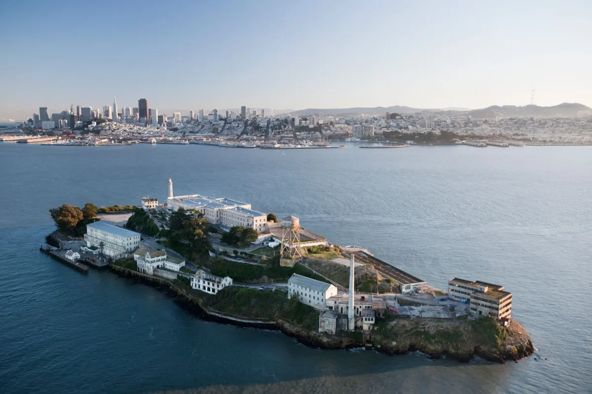 Aerial view of Alcatraz Island with historic prison buildings, lighthouse, and San Francisco skyline