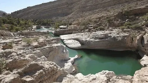 Aerial view of Wadi Bani Khalid in Oman with turquoise pools surrounded by palm trees and limestone cliffs