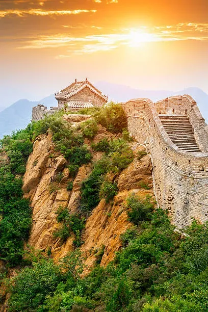Great Wall of China winding over green mountains at sunset