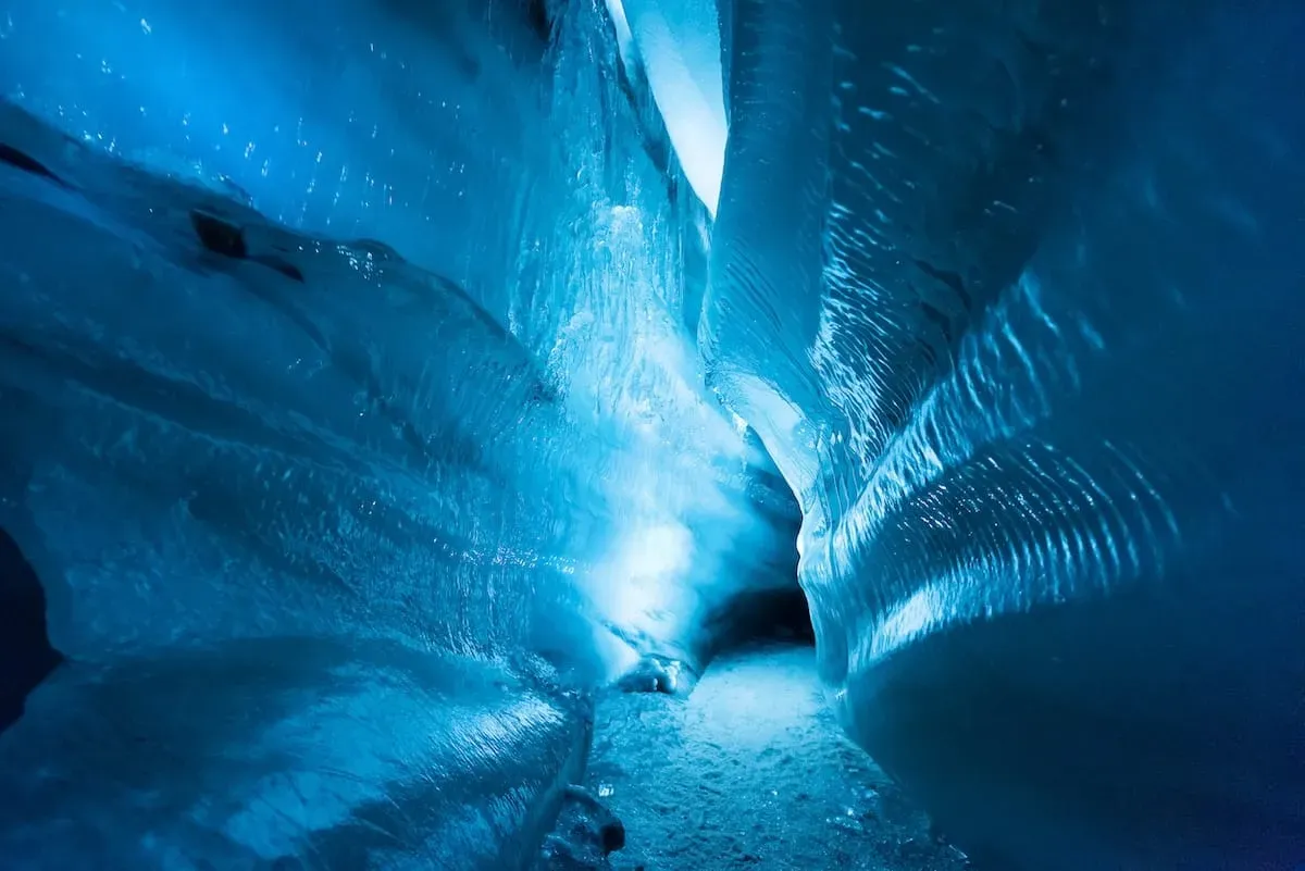 Vivid blue ice formations inside Svalbard ice caves with smooth sculpted walls in Norway