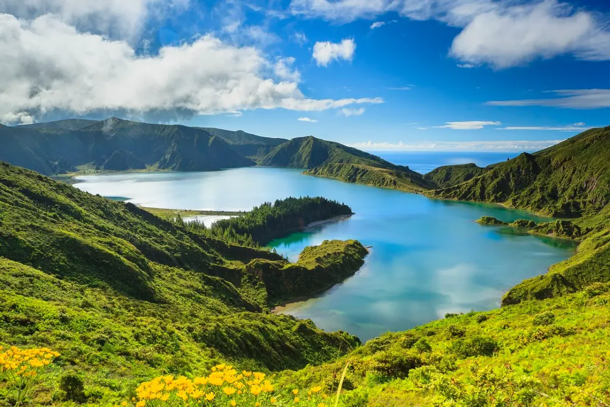Panoramic view of Lagoa do Fogo crater lake with turquoise-blue water surrounded by green volcanic hills on São Miguel Island, Azores, Portugal