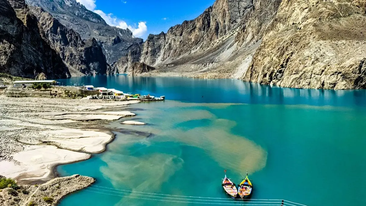 Panoramic view of Attabad Lake Pakistan with turquoise water surrounded by Karakoram mountain peaks under blue sky