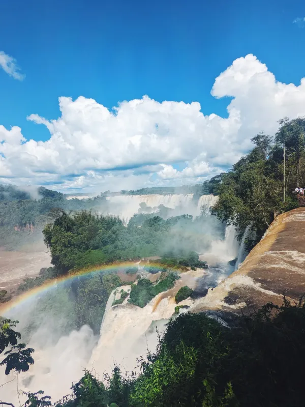 Devil's Throat at Iguazu Falls Argentina with a rainbow appearing through the mist surrounded by lush green rainforest
