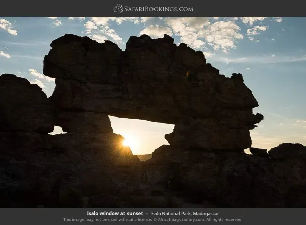 Isalo Window rock formation at sunset with orange and purple sky over sandstone landscape