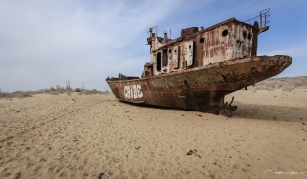 Rusting abandoned fishing trawler shipwreck stranded in the dried-up desert seabed of the former Aral Sea at Moynaq Ship Graveyard Uzbekistan