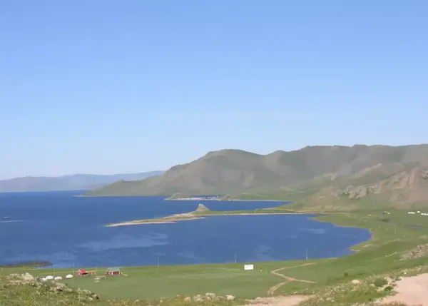 Turquoise waters of White Lake (Terkhiin Tsagaan Nuur) in Mongolia with rolling green hills under a dramatic sky, a pristine volcanic crater lake in Arkhangai Province