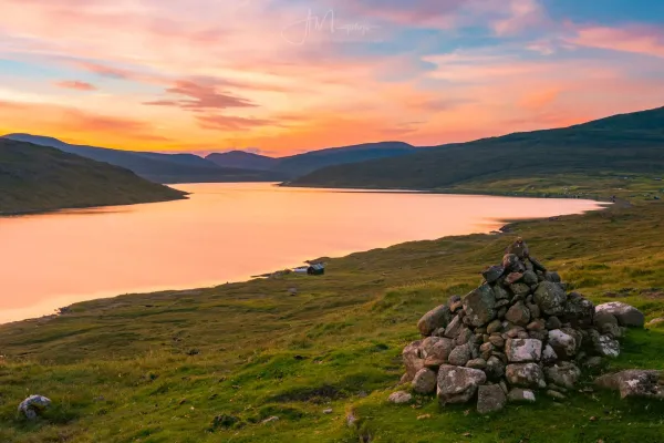 Sunset over Lake Leitisvatn with Bøsdalafossur waterfall plunging into the Atlantic Ocean on Vágar, Faroe Islands