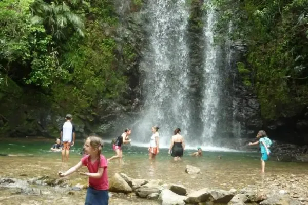 Tadake Falls cascading down a green cliff into a pool in Okinawa Japan